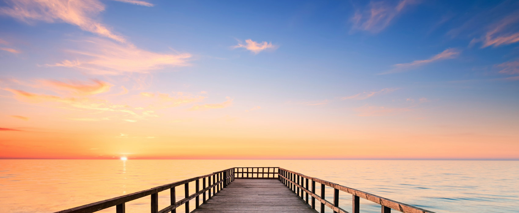 A wooden pier reaching toward the horizon at dawn — the path forward