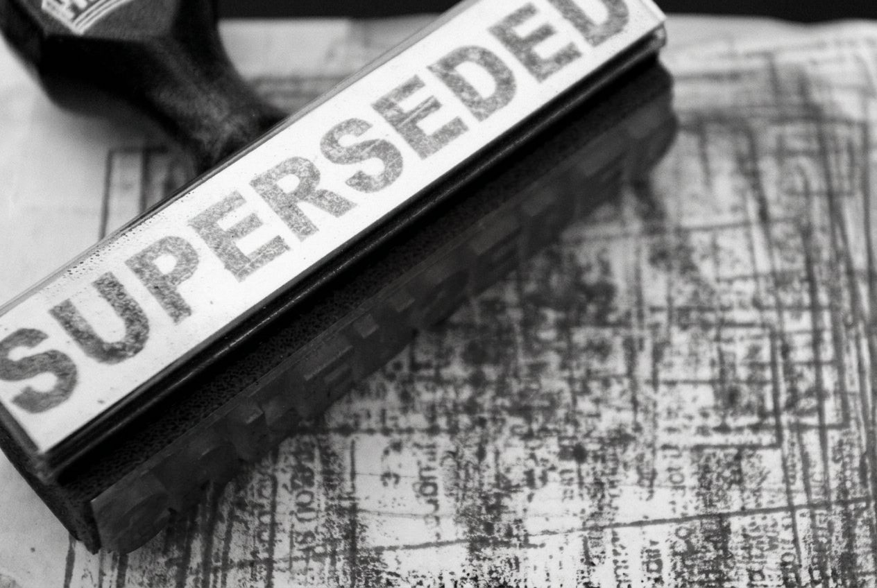 A rubber stamp bearing the word superseded resting on a stamped document.
